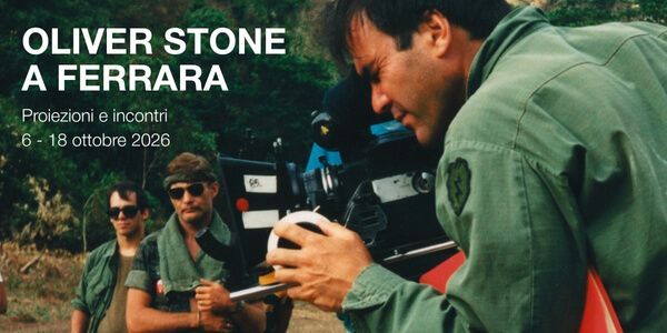 Oliver Stone a Ferrara - Proiezioni e incontri dal 6 al 18 ottobre 2026. Foto da un set cinematografico: il regista Oliver Stone, in camicia militare verde, regola una cinepresa in primo piano; alle sue spalle due uomini in divisa e occhiali da sole in mezzo alla vegetazione.